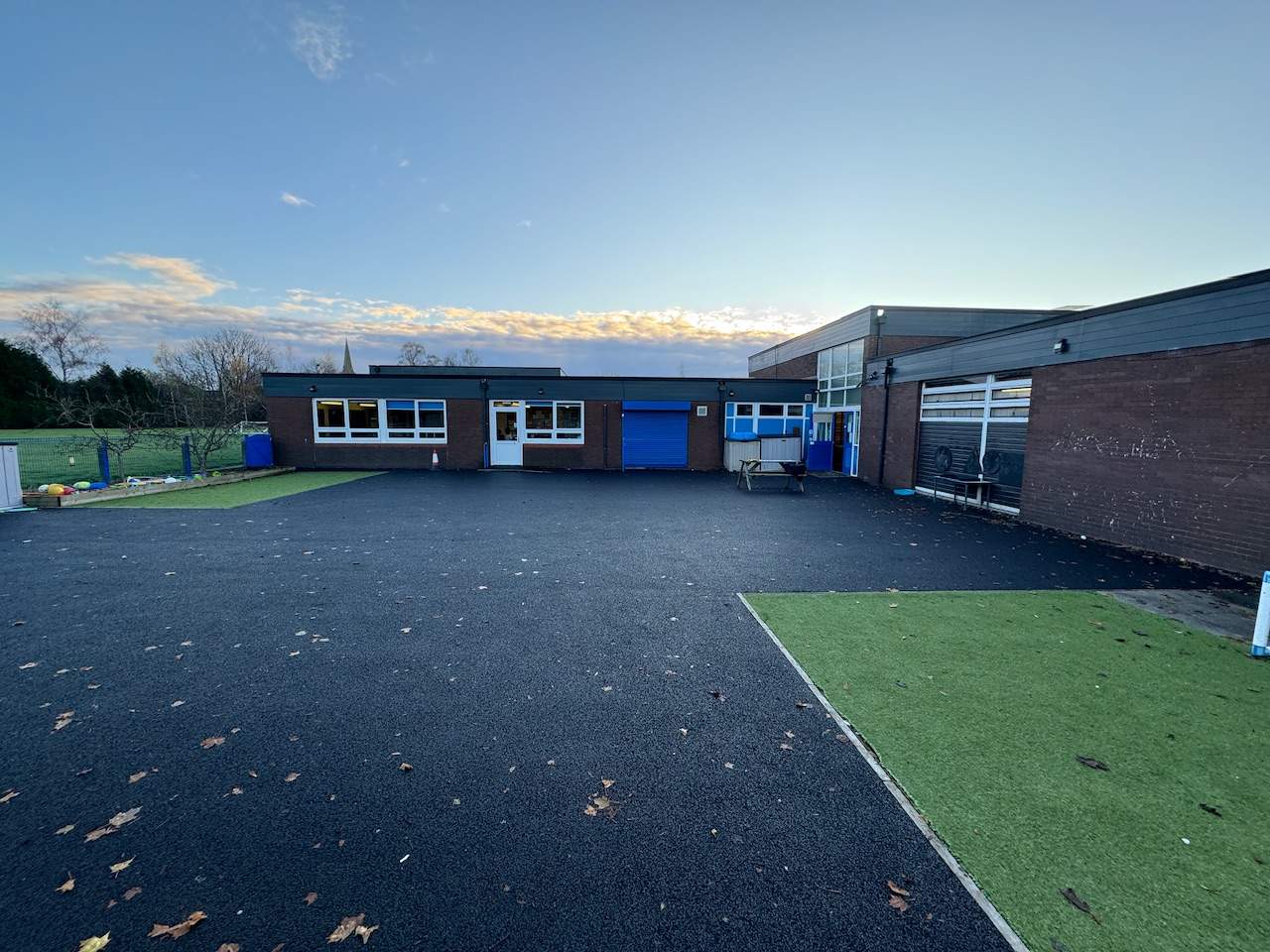 A plain tarmac playground with a small patch of artificial grass at St Peter's Primary School.