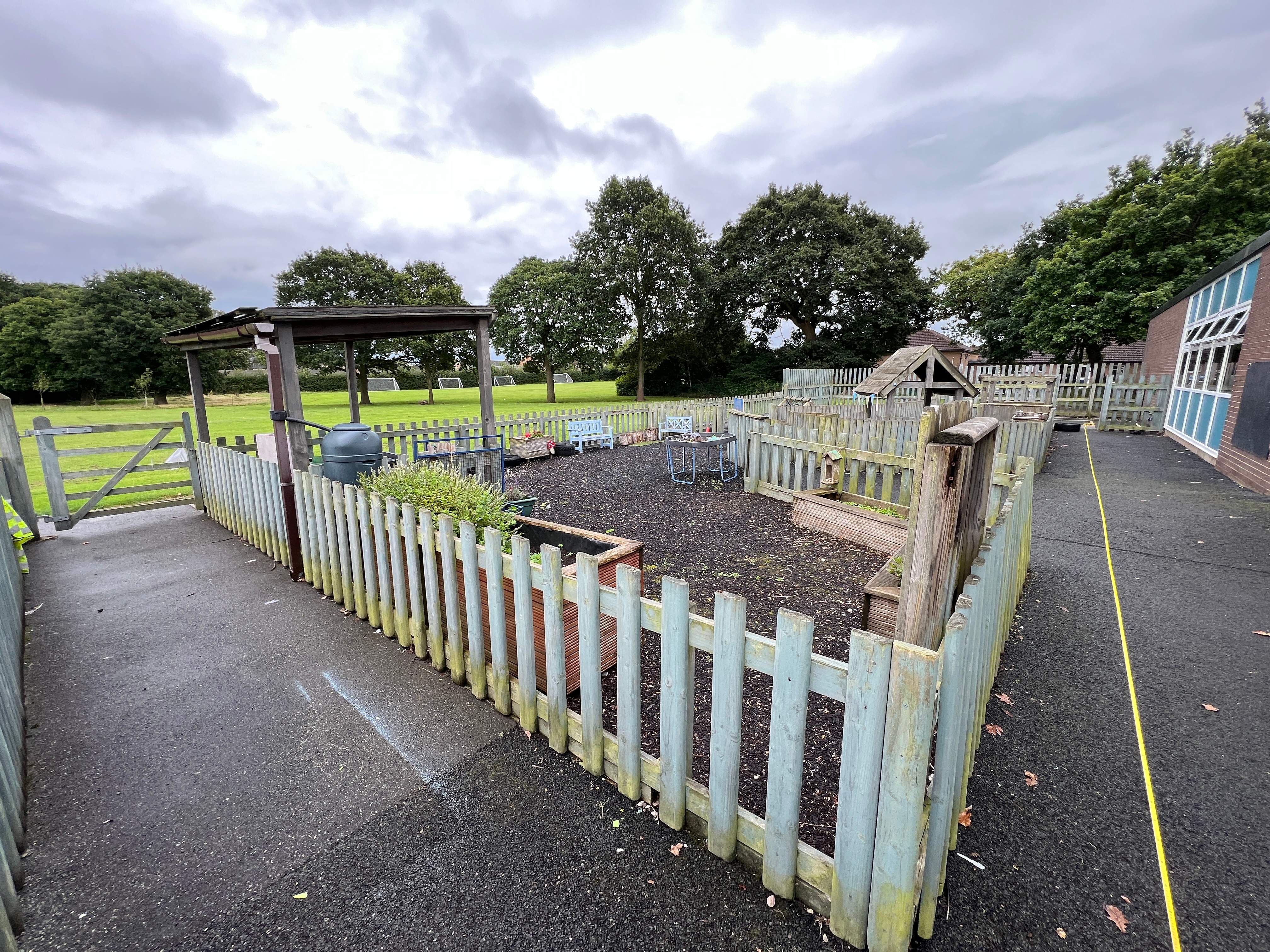 An old fenced off part of a playground, with the wooden fence showing signs of aging.