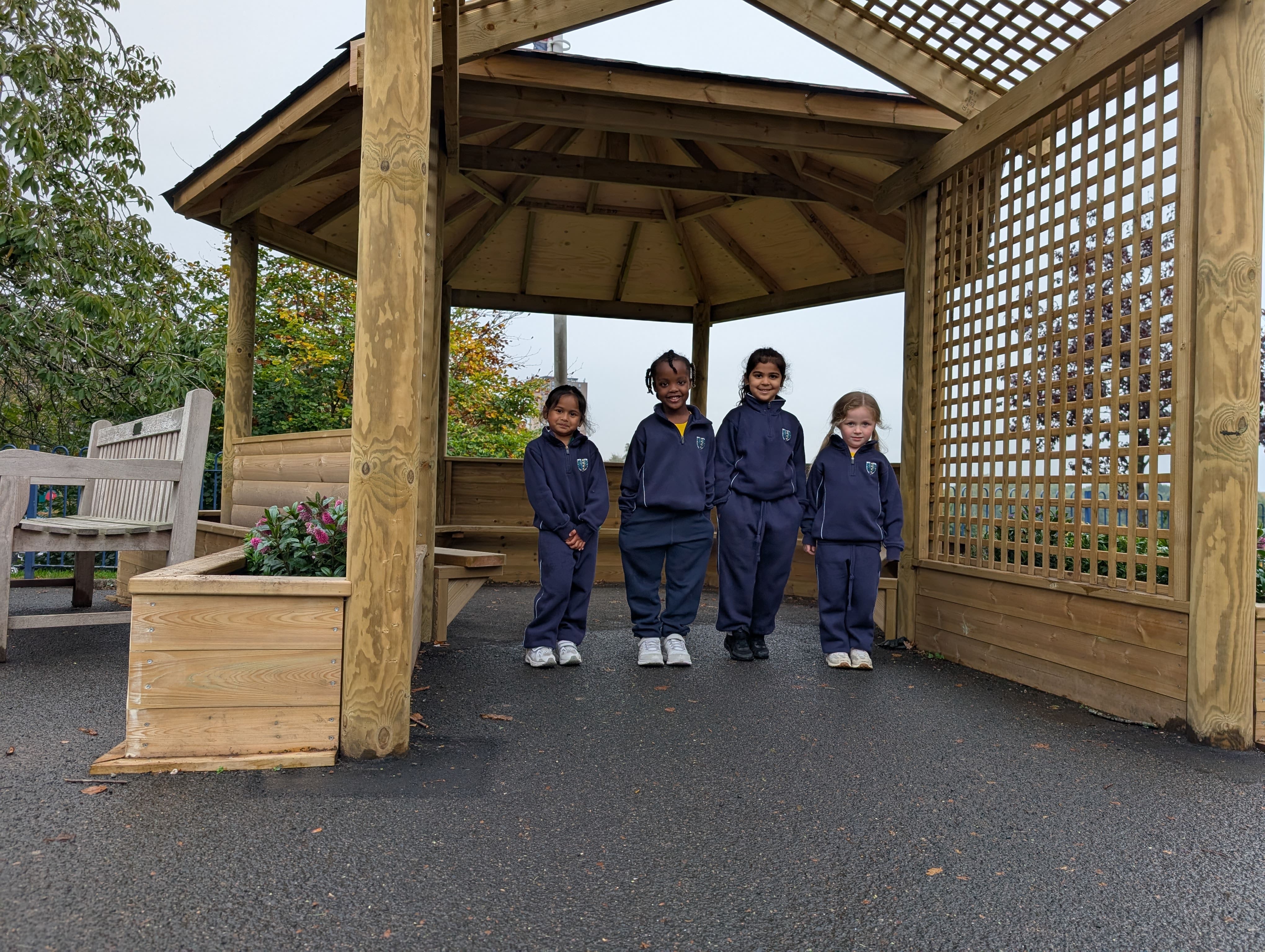 A small group of children are stood underneath the Sensory Garden Gazebo structure.