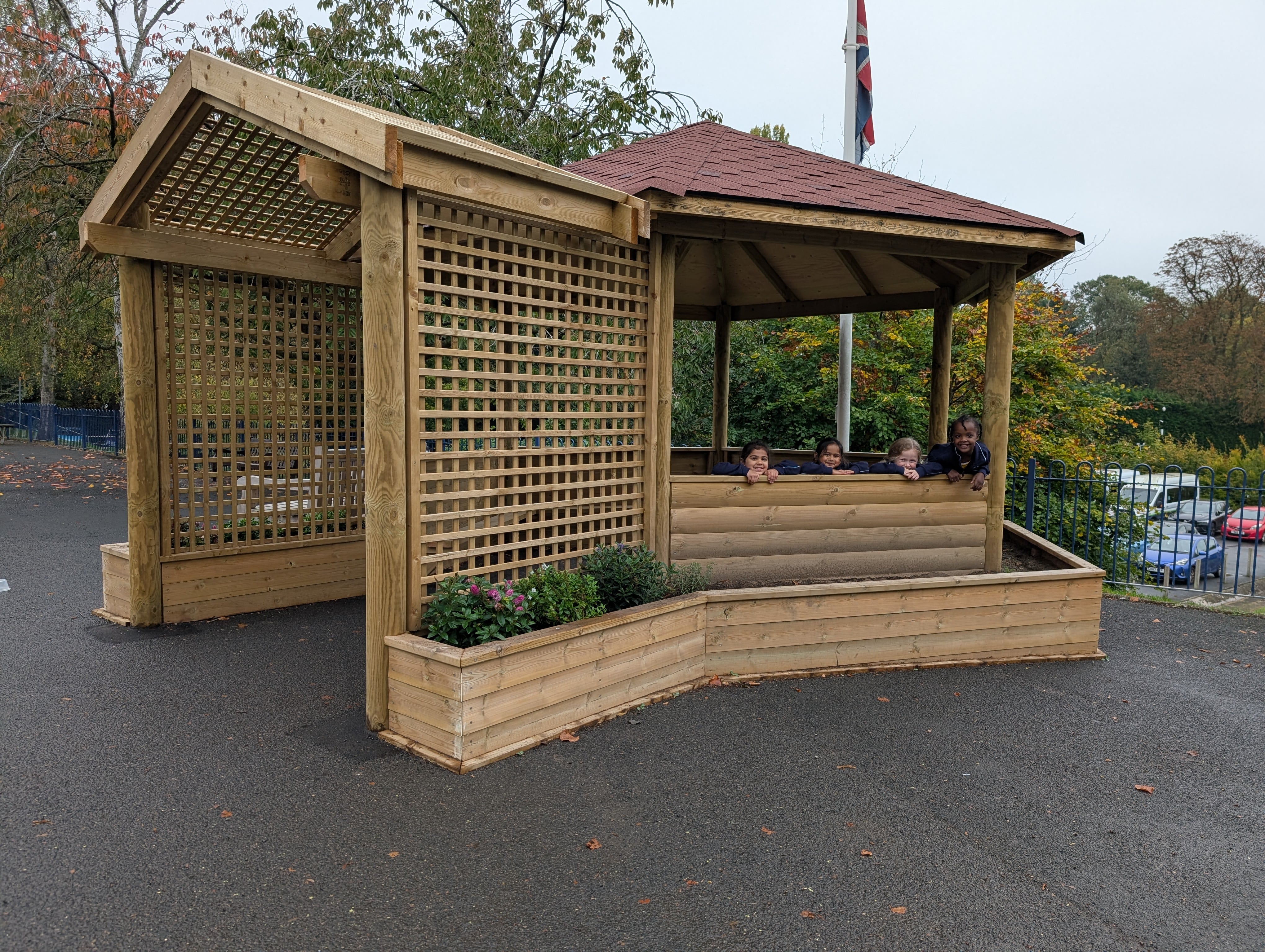 An outside shot of the Bespoke Sensory Garden Gazebo. The children are waving from inside.
