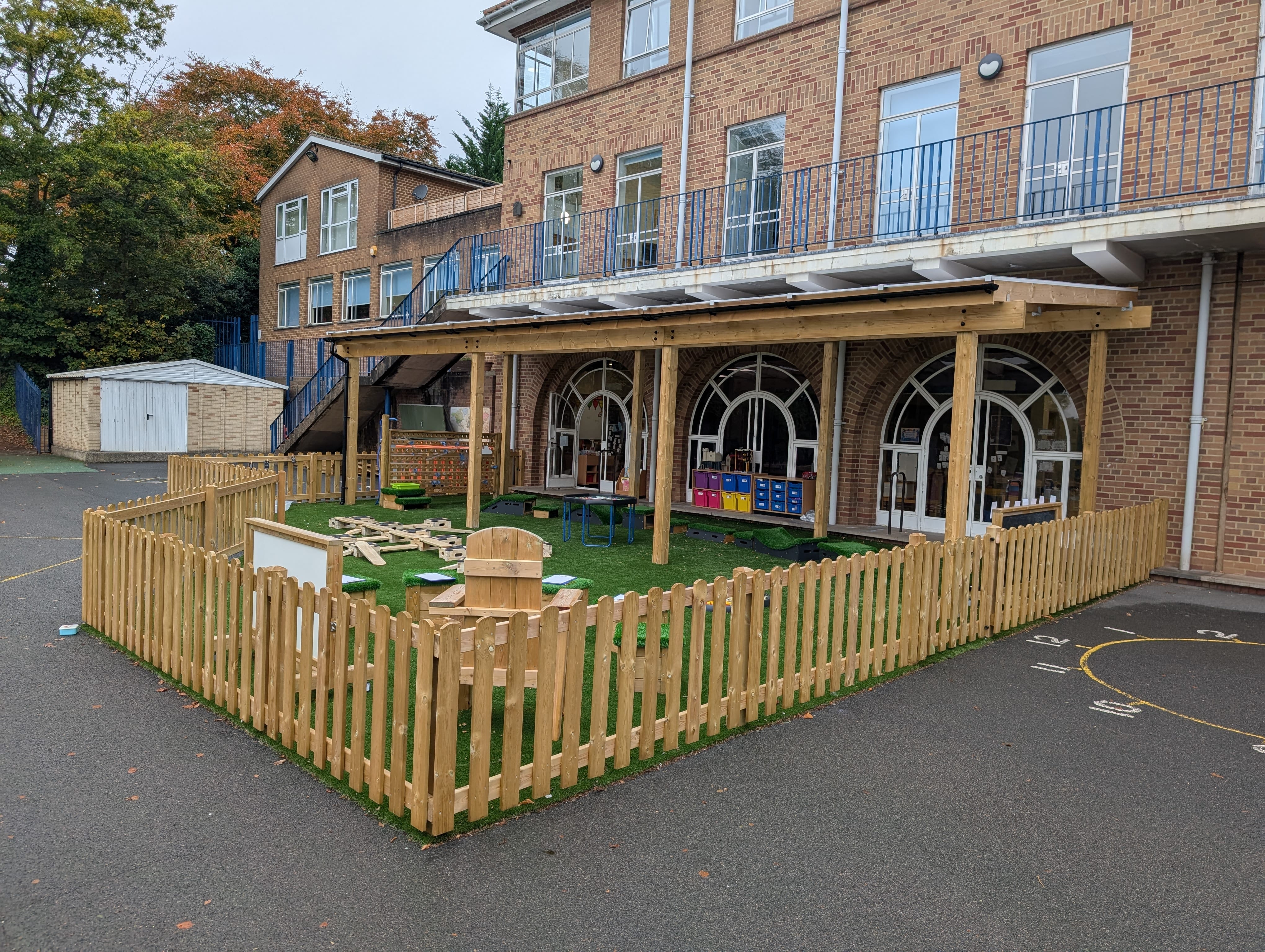 A wide shot which showcases the brand new EYFS playground, with the fencing and new surfacing.