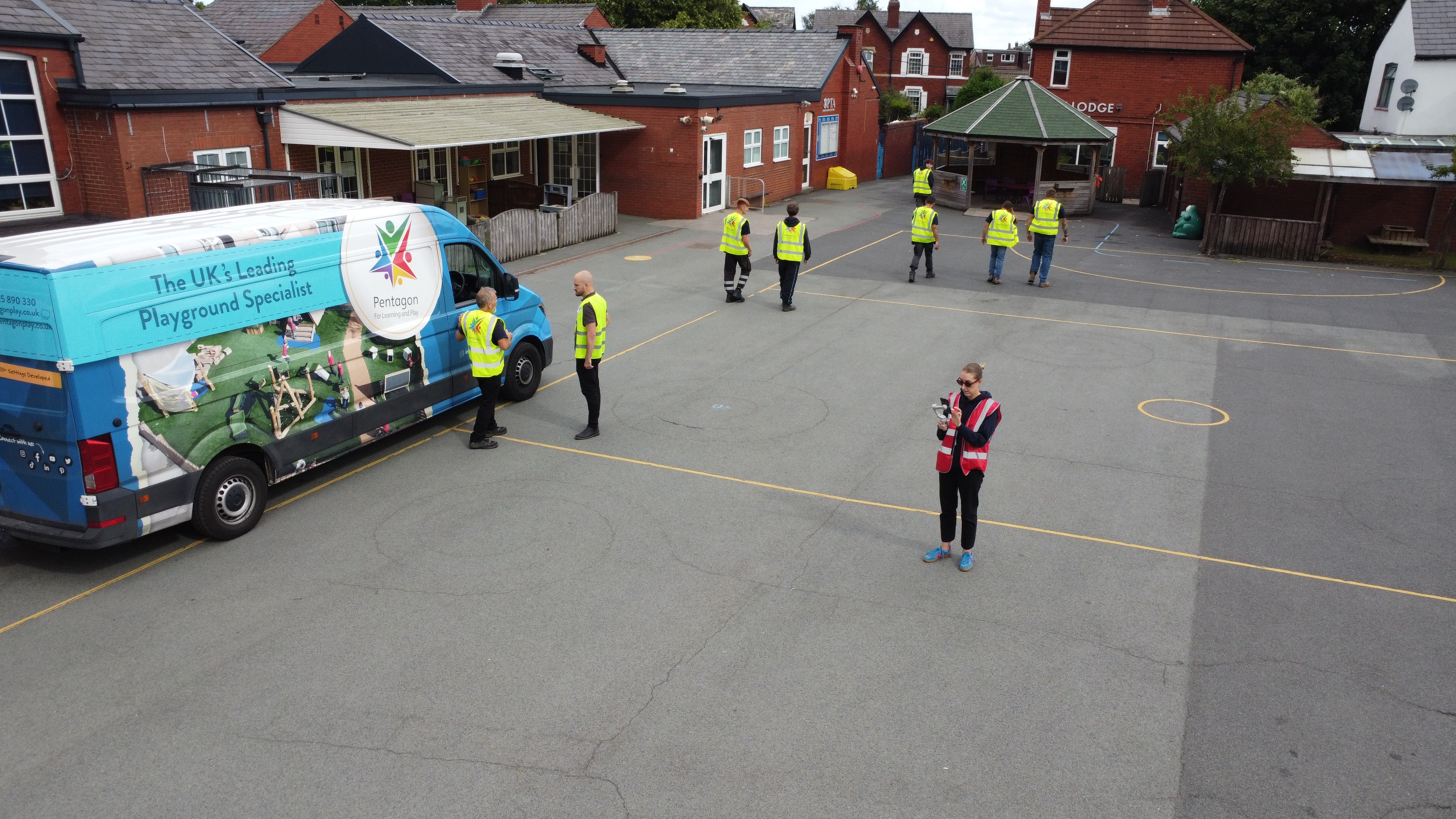 Pentagon Play van on the tarmac playground as installers walk around.