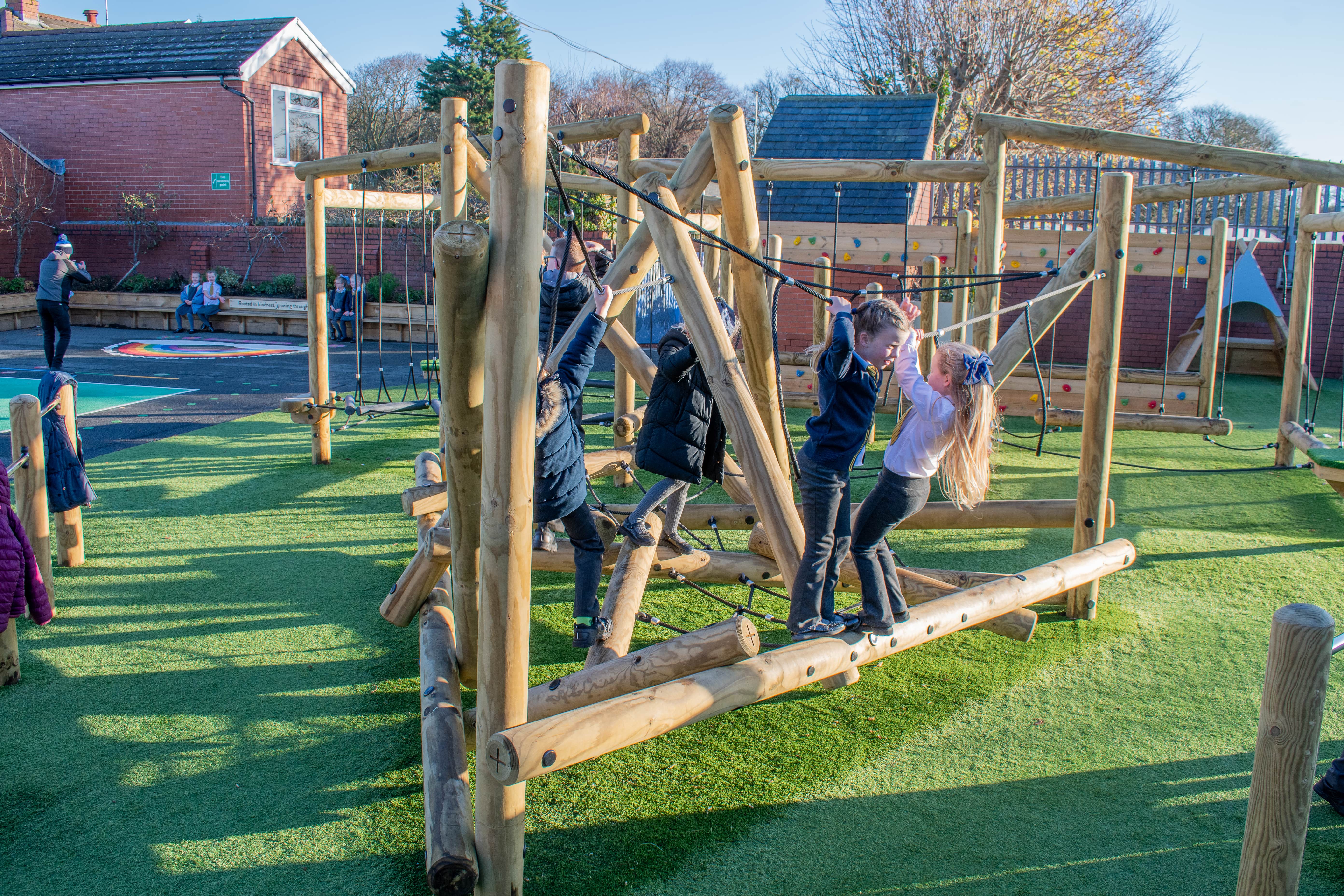 A large group of kids are playing on a climbing frame.