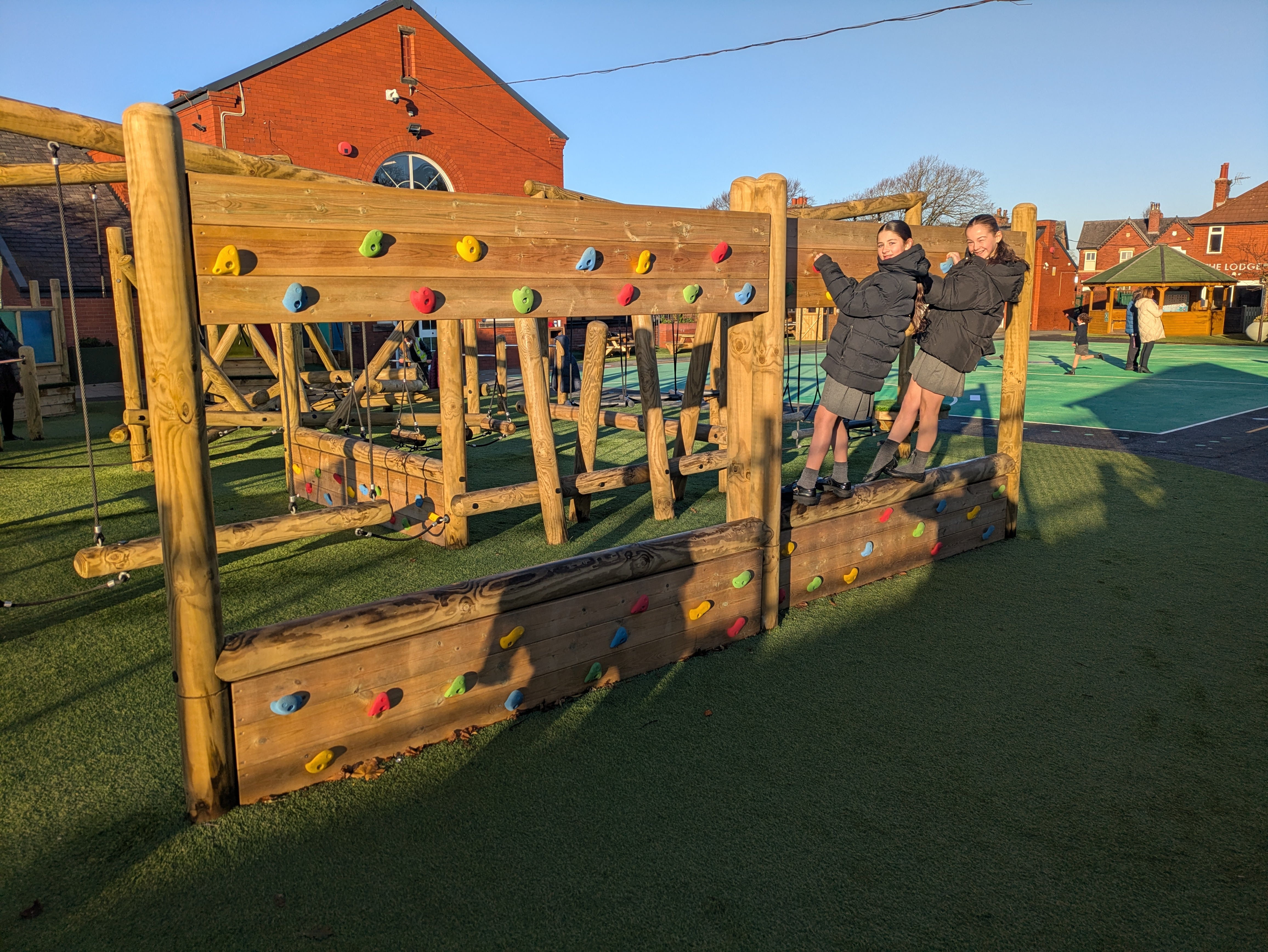 Two children are climbing on a climbing wall and looking at the camera.