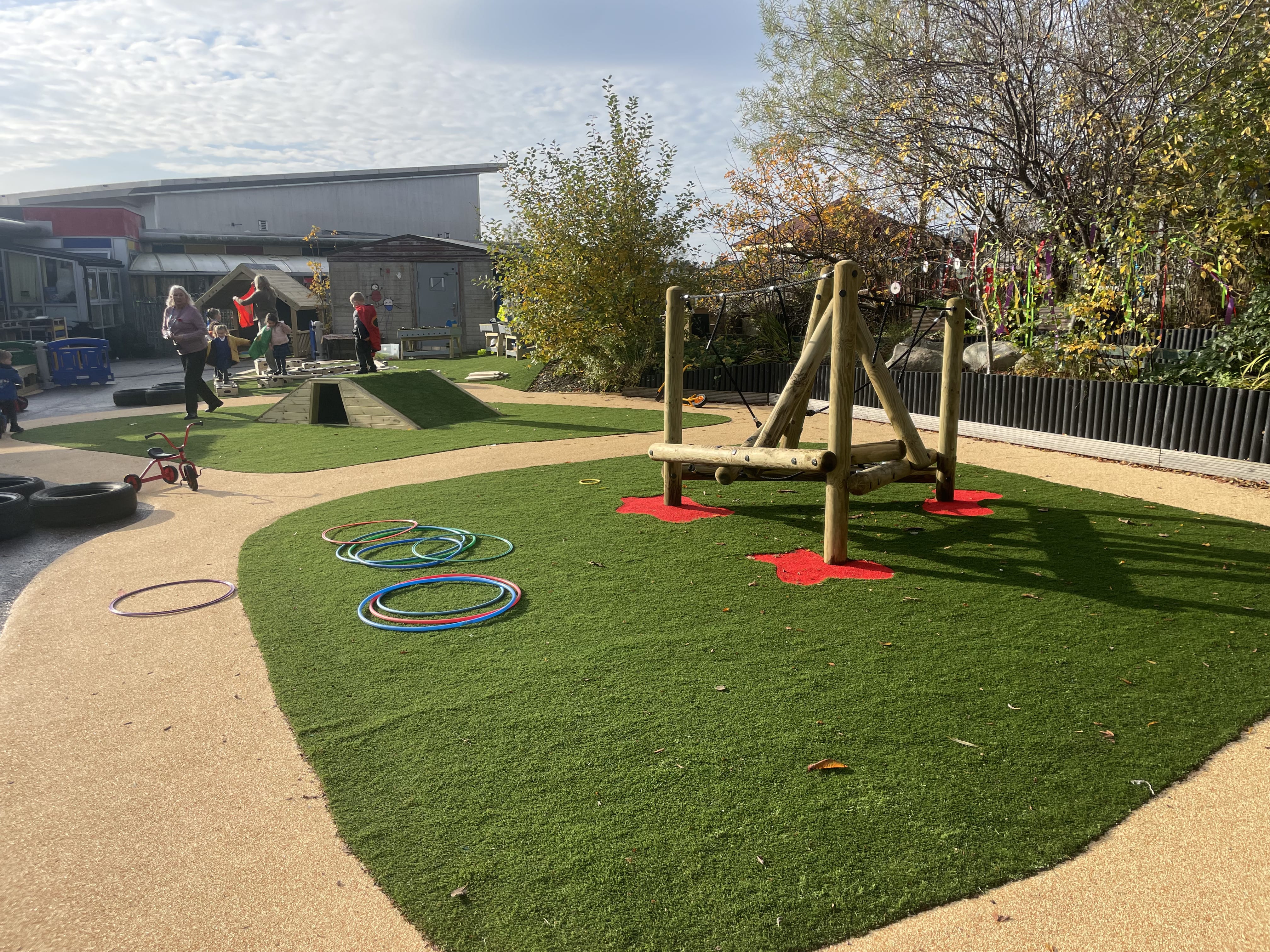A climbing frame that has been installed in the centre of a wetpour roadway at Kingsland Primary, with children playing in the background.