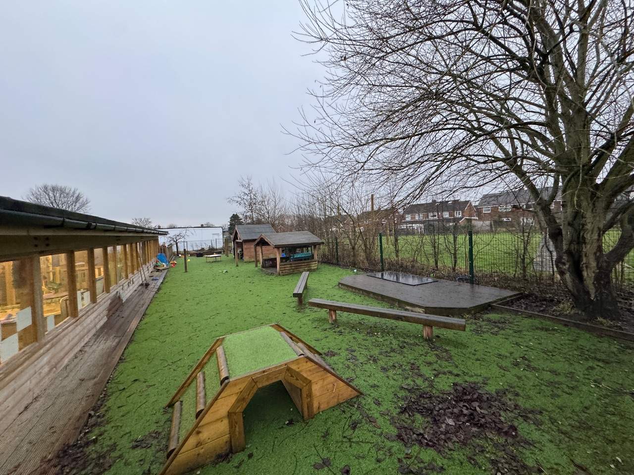 An old playground with green wetpour surfacing and a few bits of play equipment.