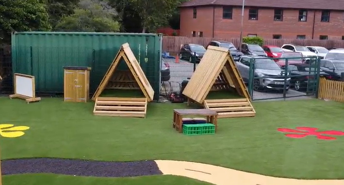Two learning dens have been placed on artificial grass, creating a secluded area for outdoor reading.