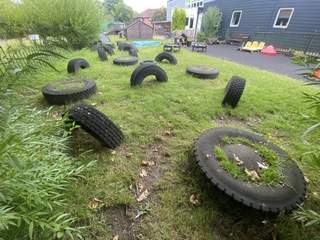 A variety of tires that have been placed on the grass, with the grass starting to overgrow them.