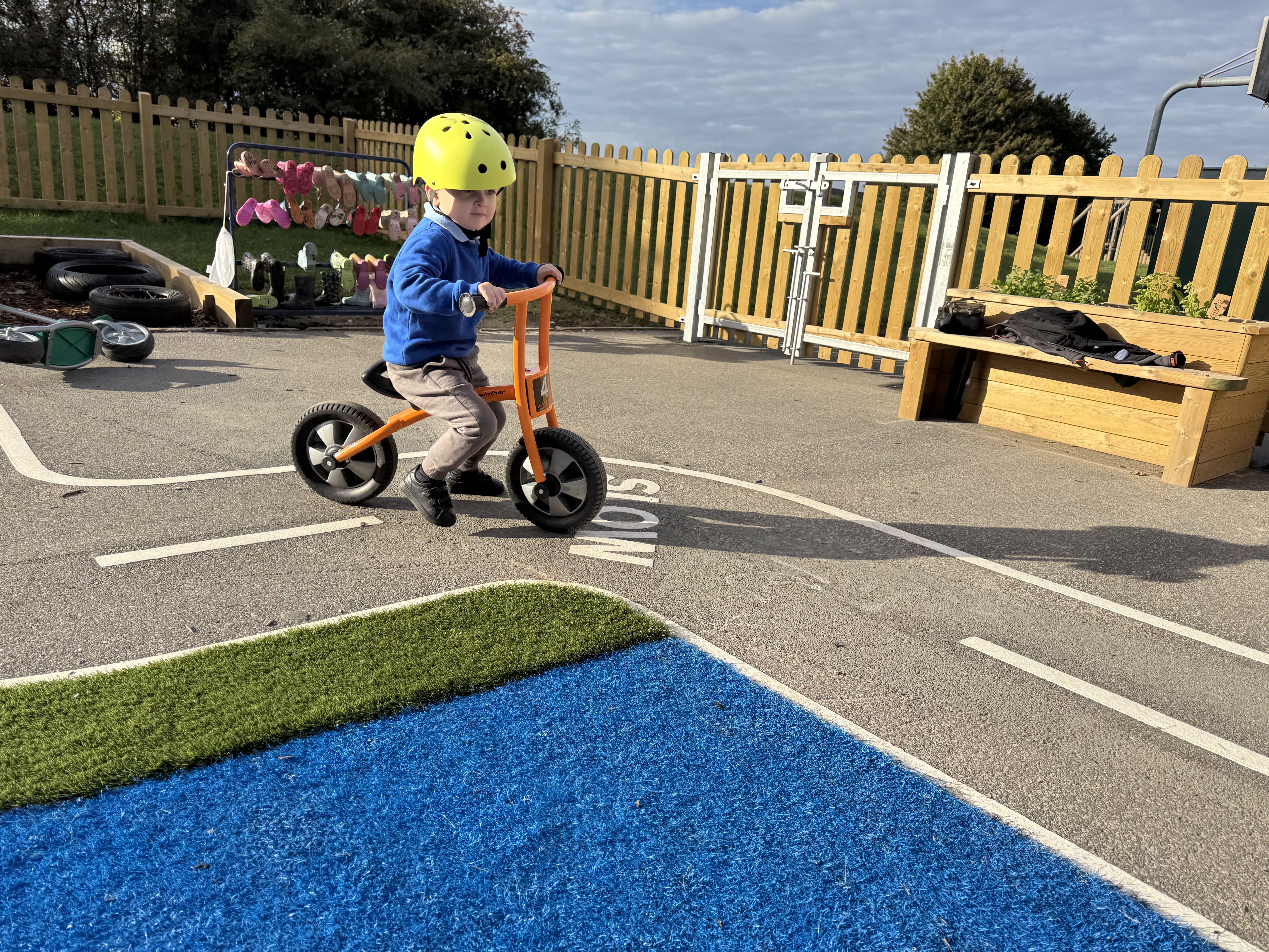 A little boy is riding on a tricycle, following the road markings laid out on the playground.