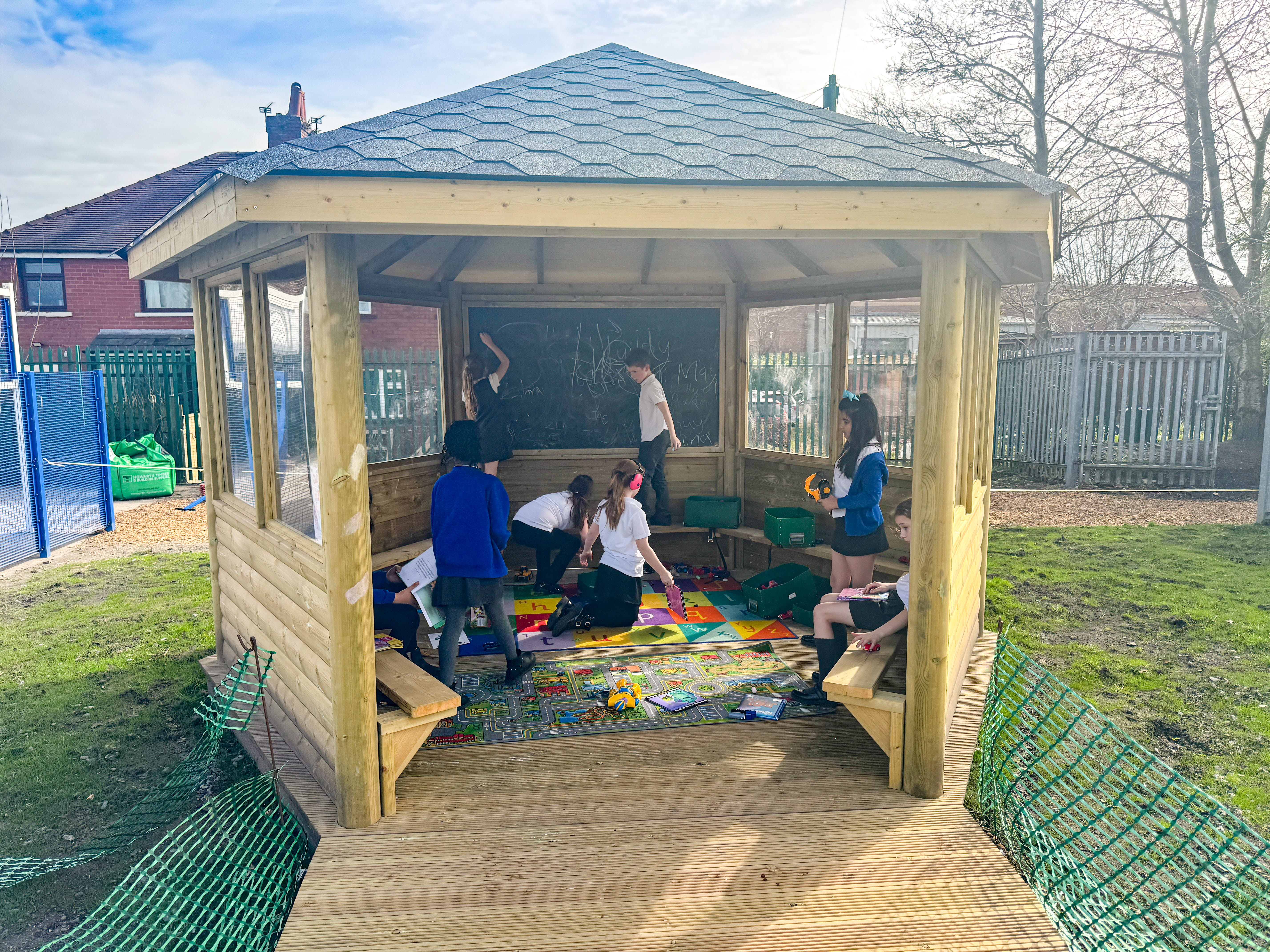 A group of children are sat inside the 5m hexagonal gazebo, playing with different toys.