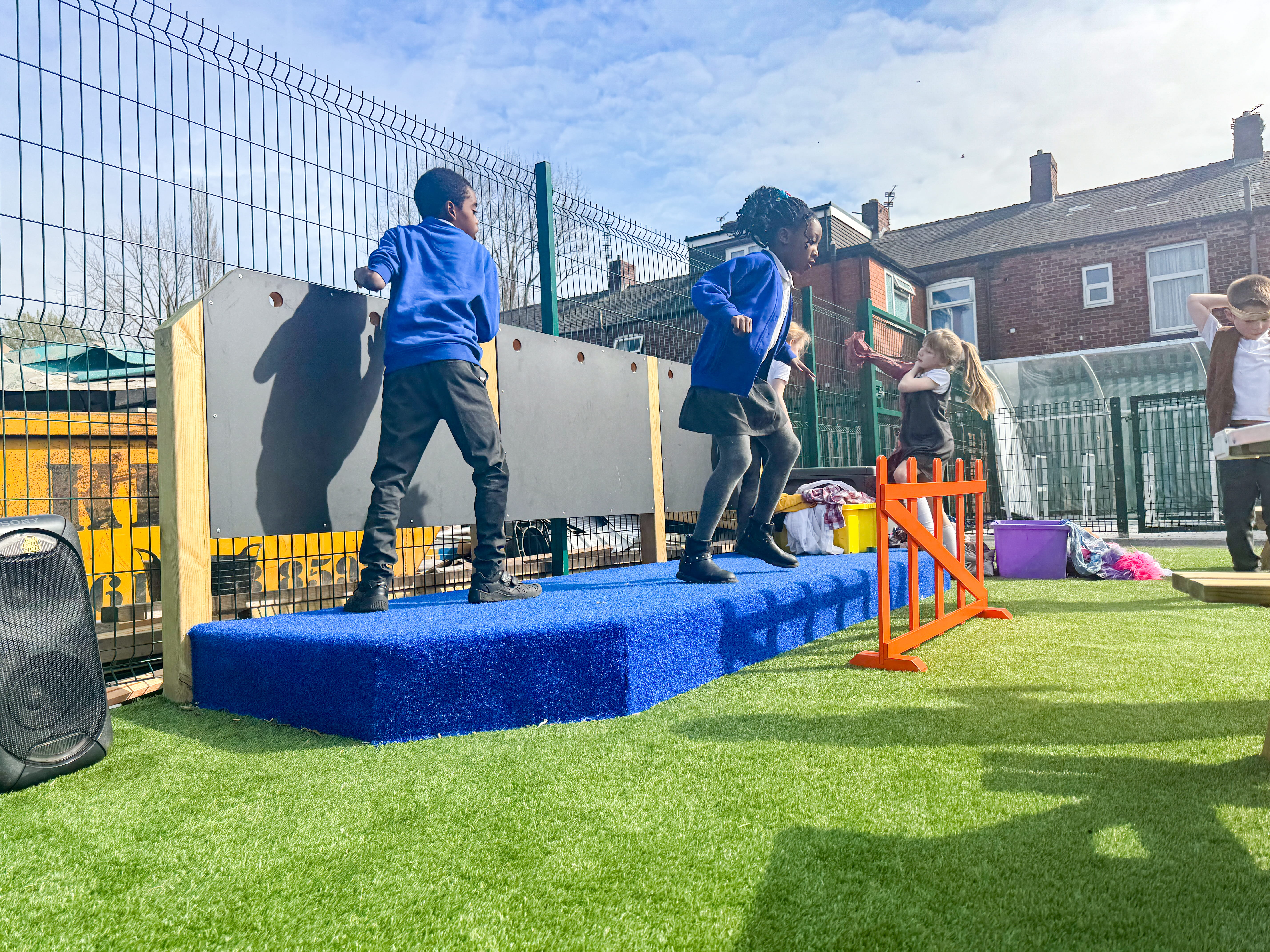 Two children are dancing on top of the Performance Stage, as other children watch them.