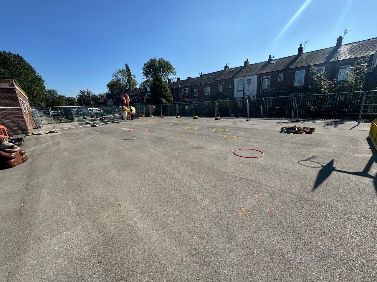 An old tarmac playground with construction fencing going around the edge.