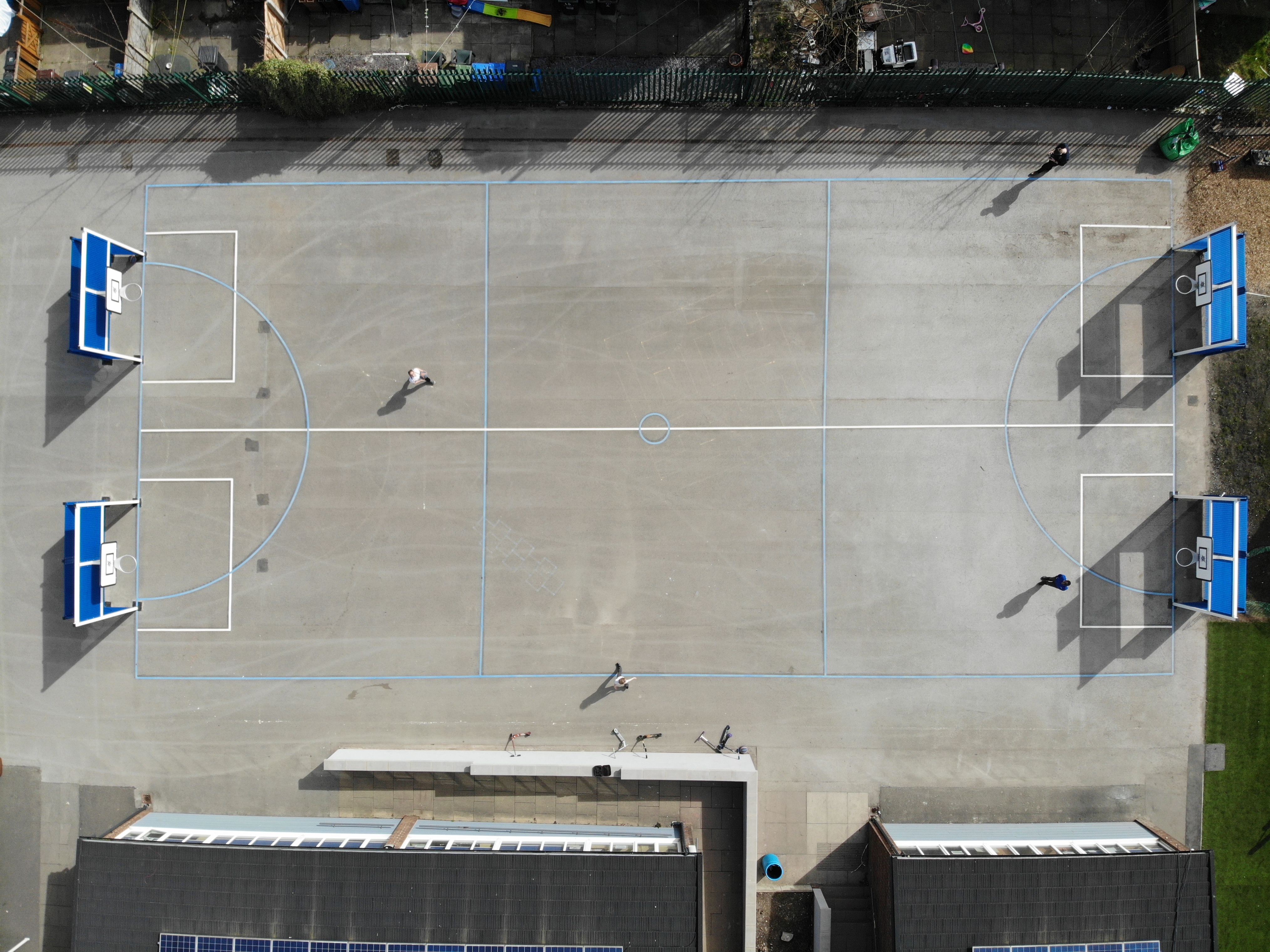 A birds eye view of the netball line markings, with the blue lines highlighting the boundaries of the court and a yellow line acting as a seperator.