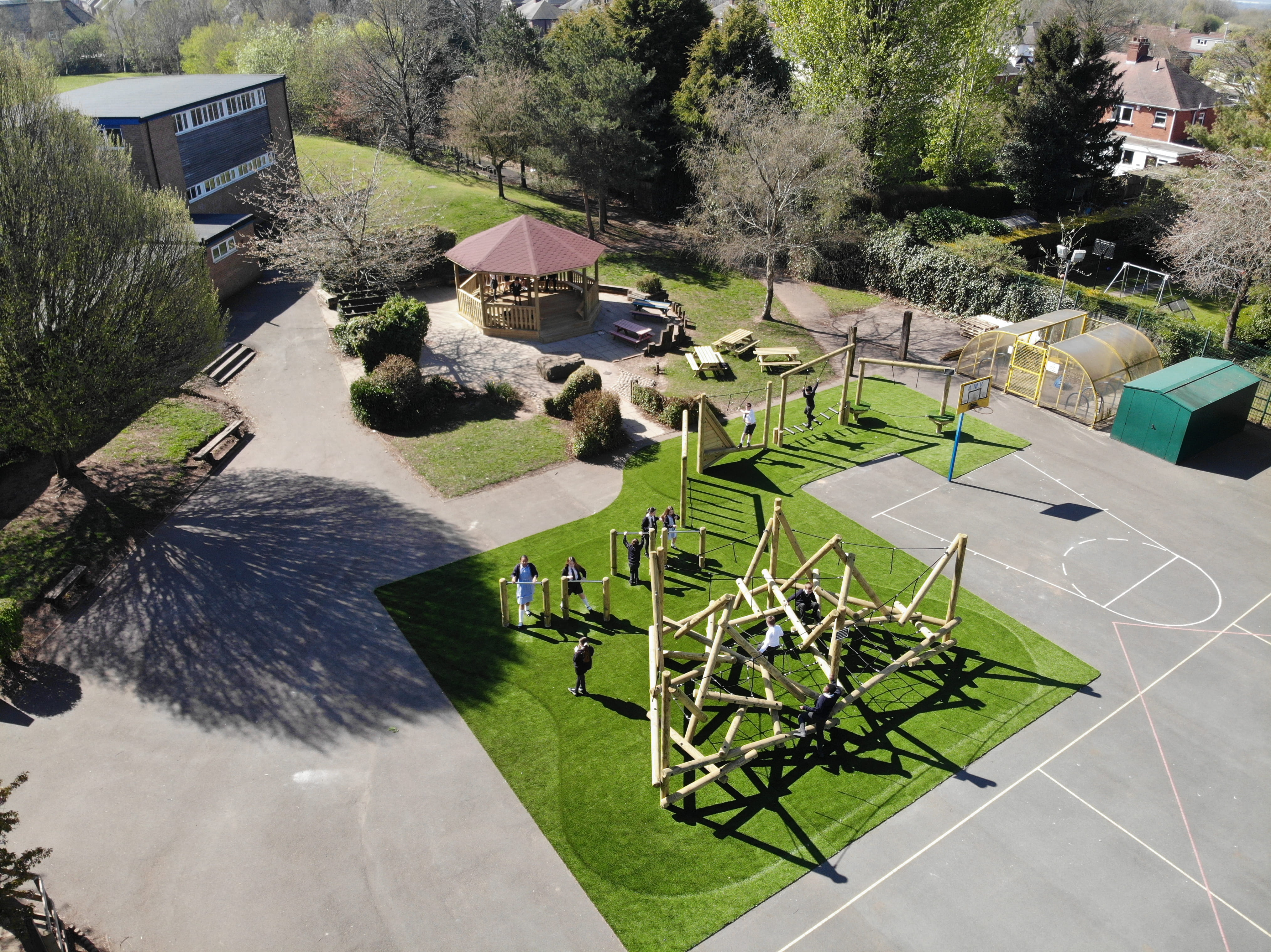 A drone shot which showcases the Helm Crag Climber on artificial grass, and an octagonal gazebo on the Weston Junior Academy playground.