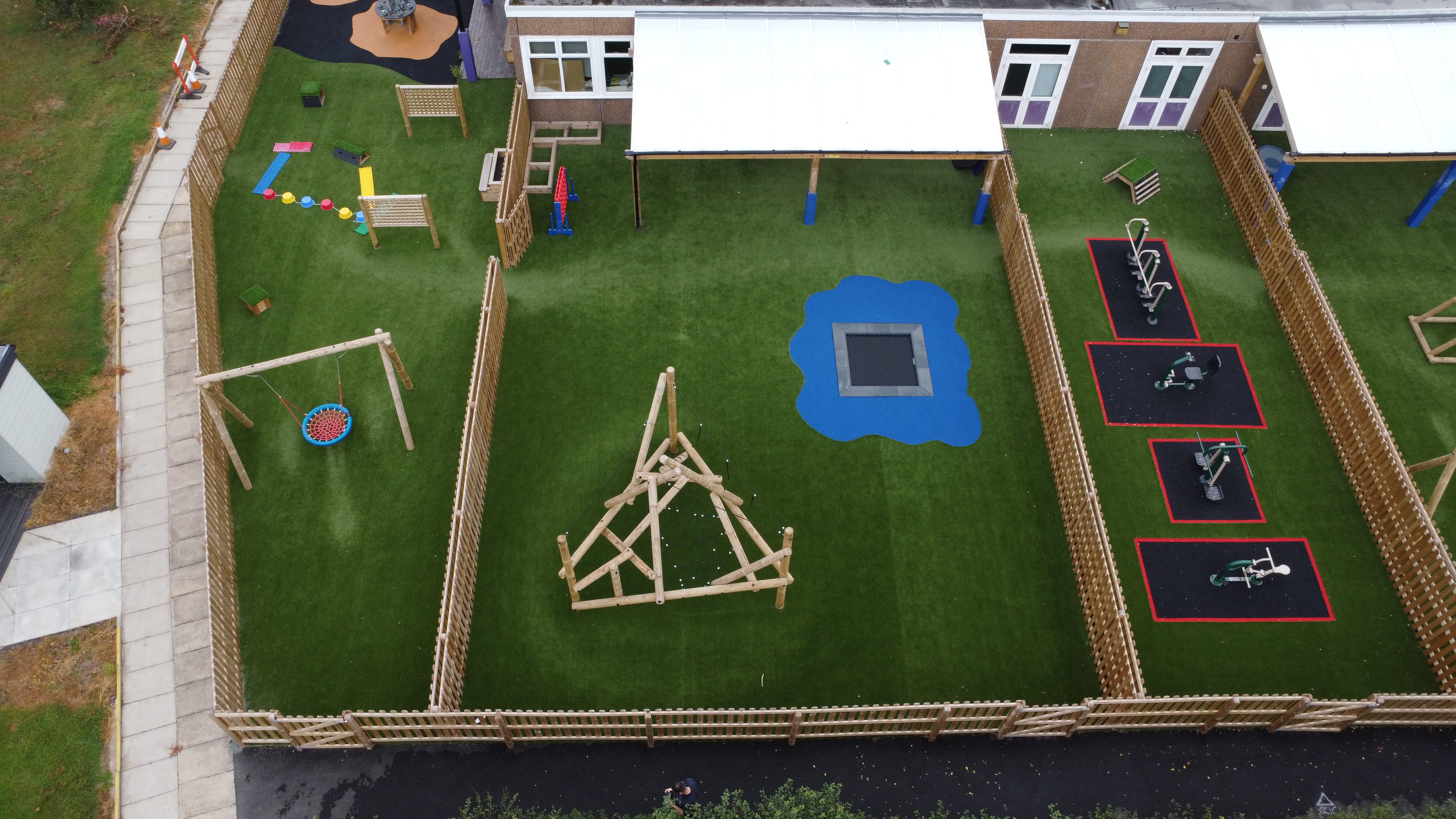 The NHu class' playground, with brand new artificial grass surfacing, with a freestanding canopy and a climbing frame.