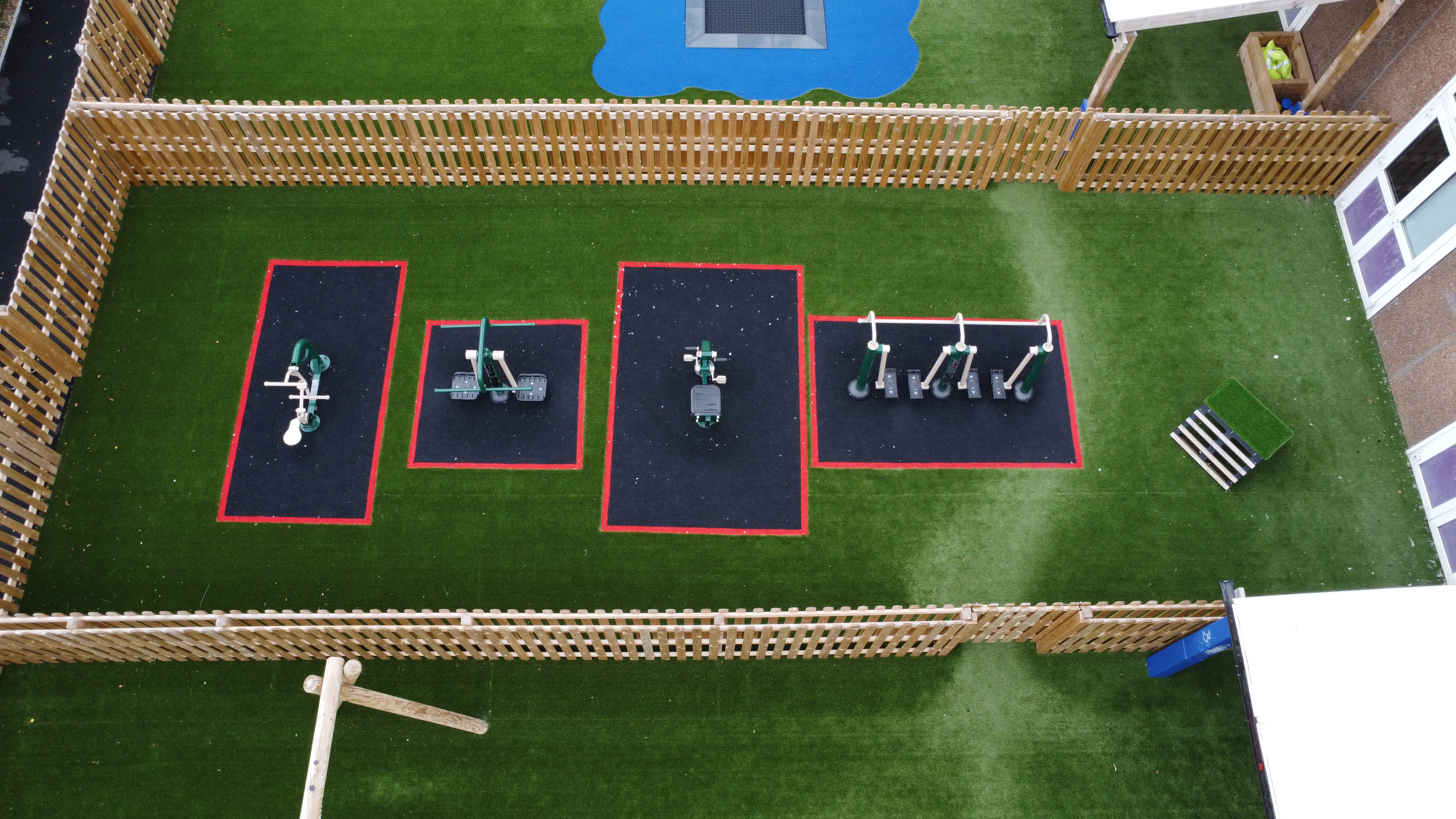 The VI Room's new playground, with artificial grass surfacing, with sections covered in wetpour. These sections have gym equipment placed on top of them.