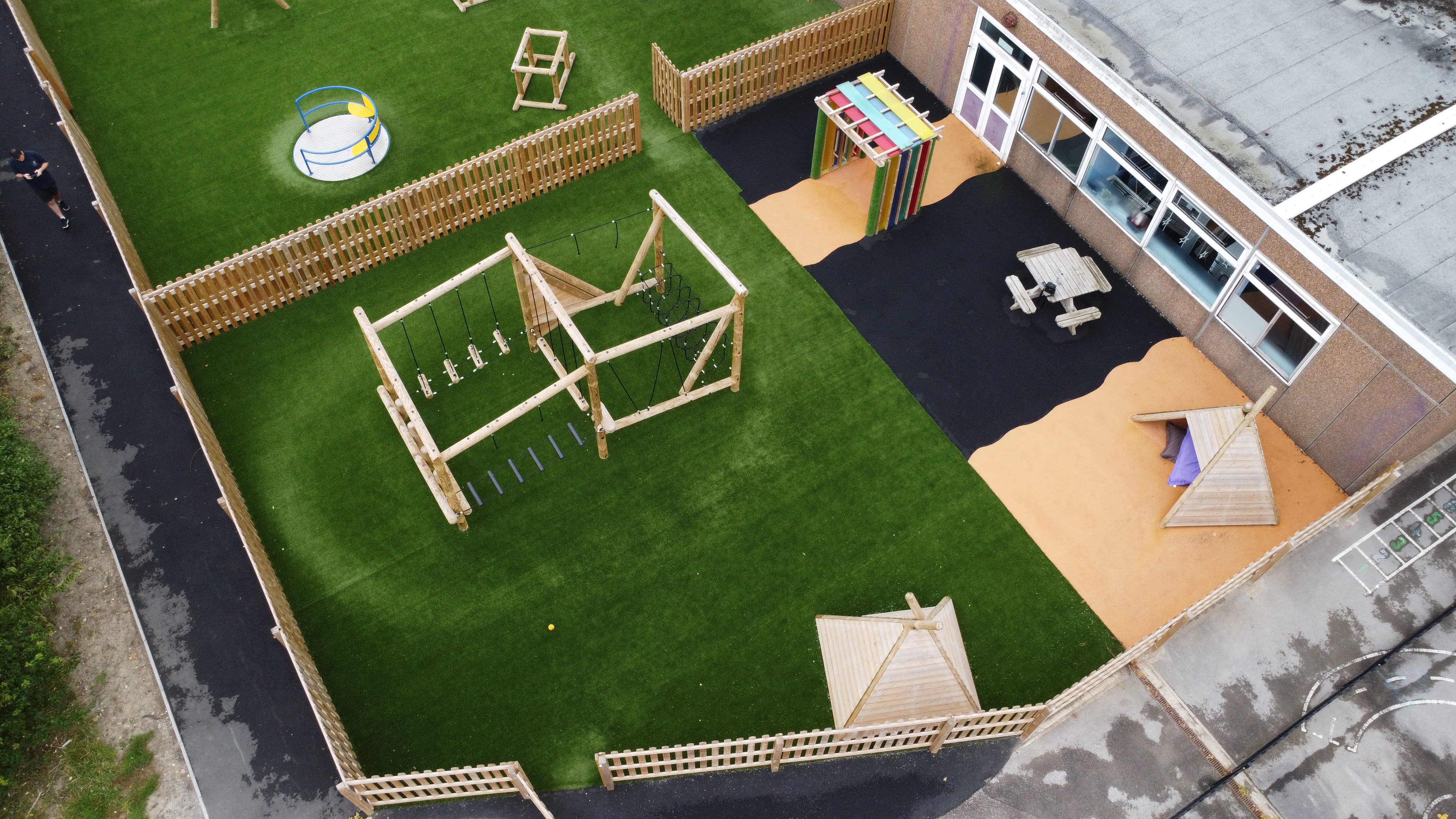 The general play area features a forest circuit installed on top of artificial grass, with the final third of the playground having wetpour surfacing and freestanding equipment.