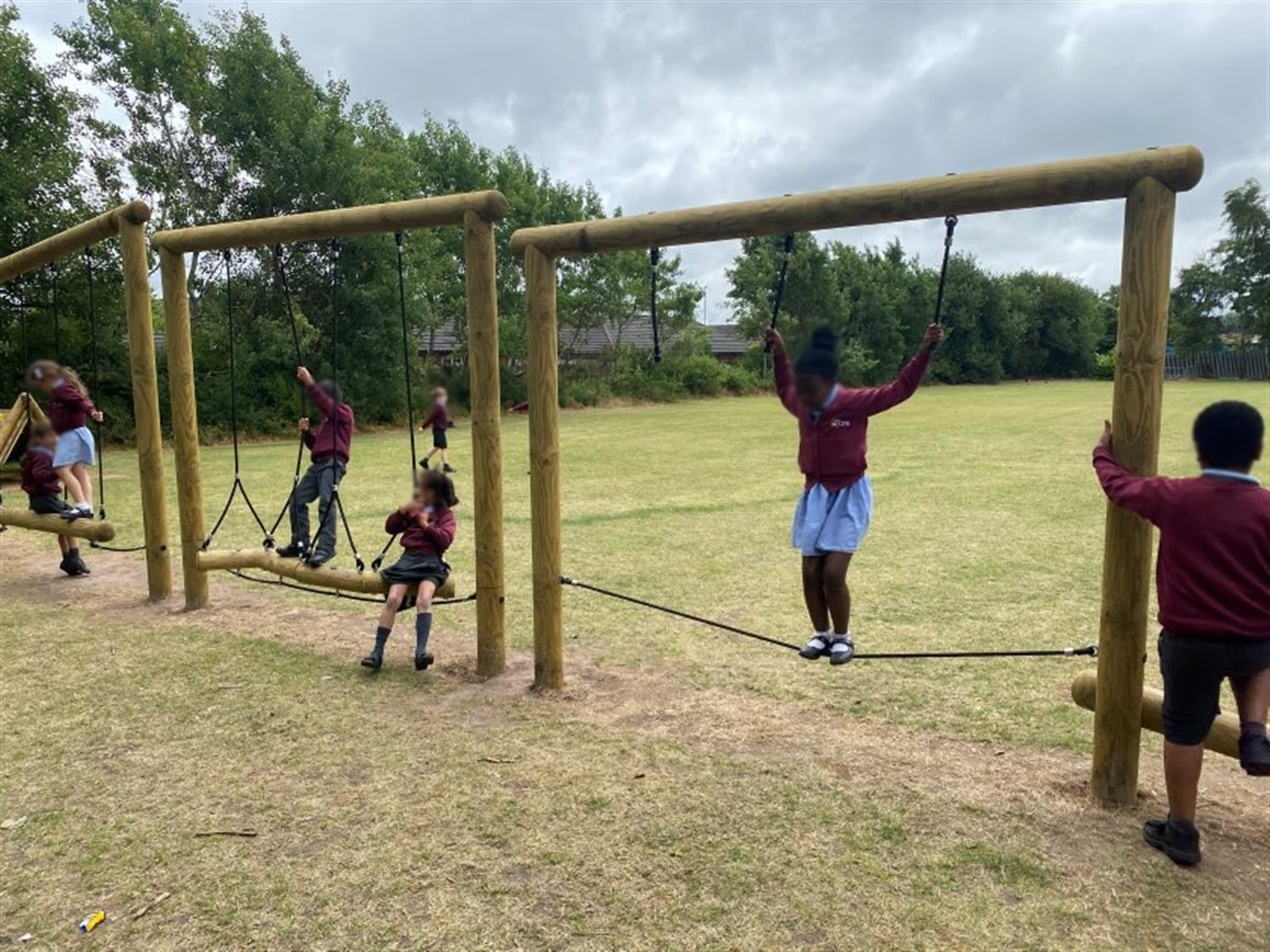 children use all areas of the trim trail and a little girl crosses the tightrope traverse