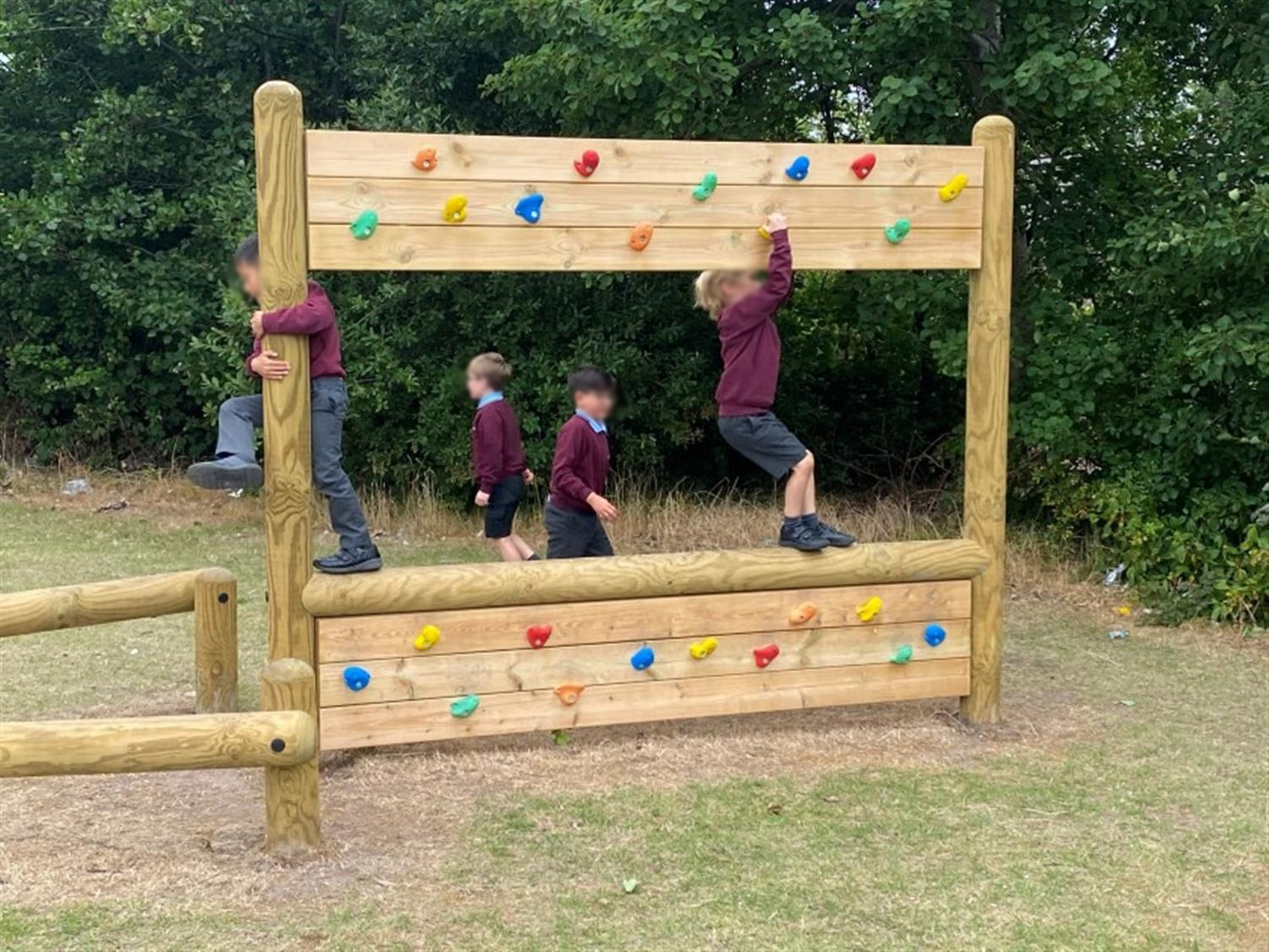 children cross the climbing wall traverse using both sides for support