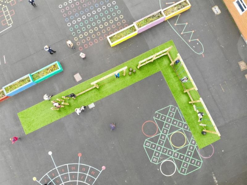 An overhead view of a nine piece trim trail installed into an L shape on the tarmac playground with vibrant green artificial grass underneath it