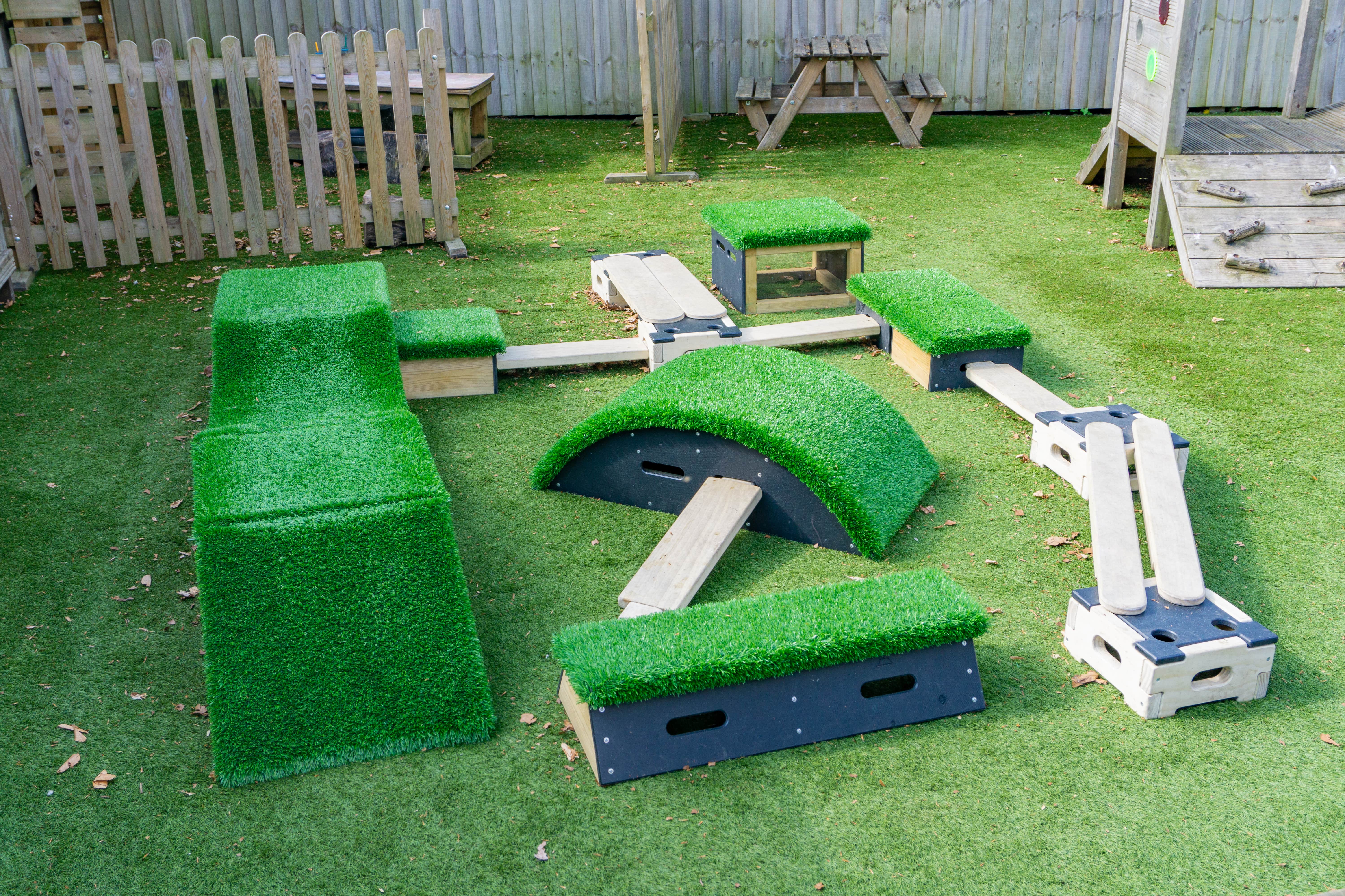 A photo showing all of the contents included within the Get Set, Go! Blocks - The Peak set. Containing 9 different blocks and some wooden planks, the set is laid out on top of an artificial grass surface.