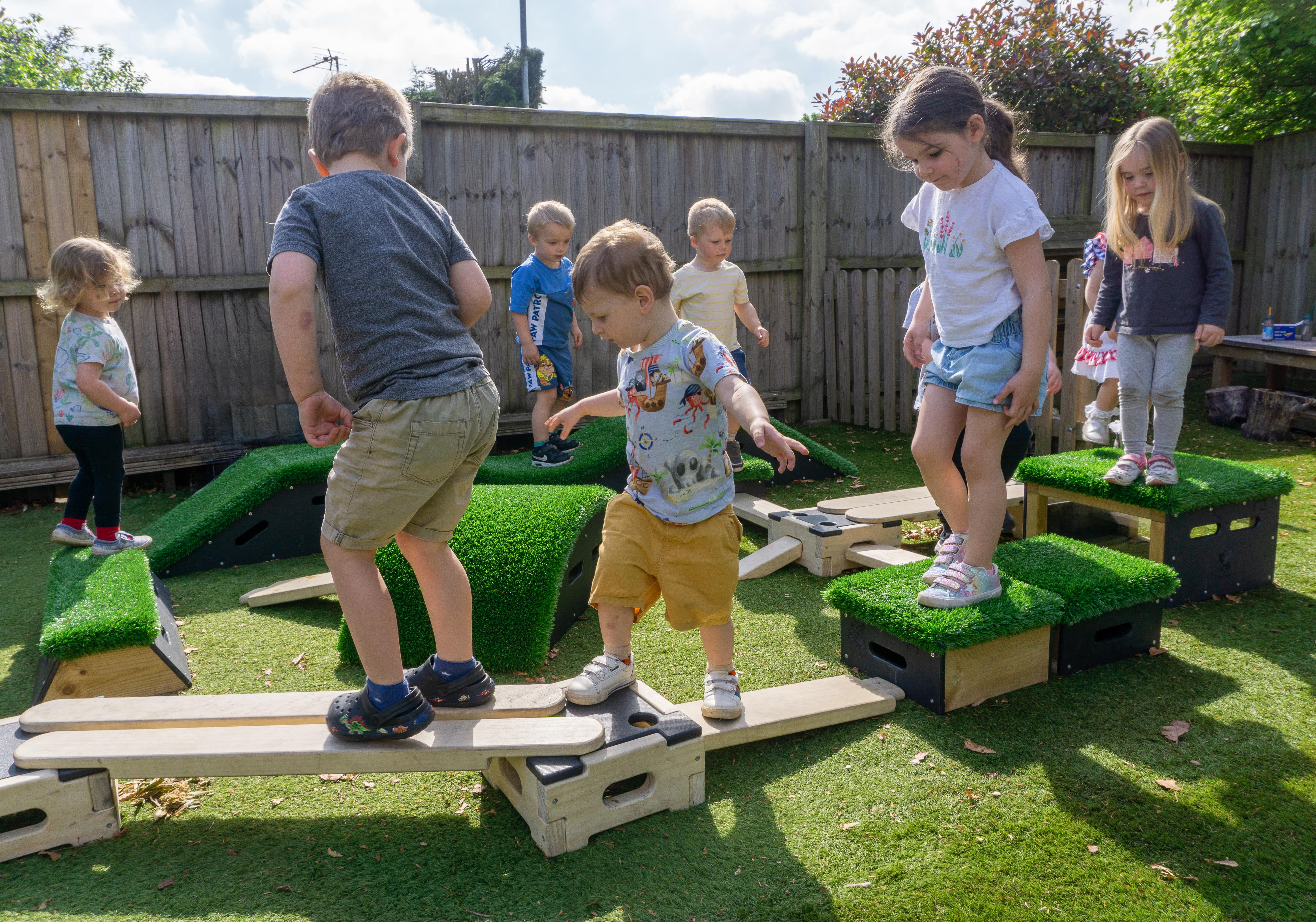 9 children are playing on the Get Set, Go! Blocks as the blocks are placed in a circle. The children are all on the equipment, paying close attention to everything.